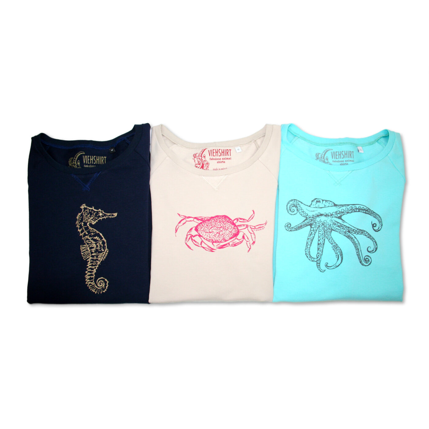 Drei zusammengelegte Sweater in den Farben dunkelblau, sand und türkis mit jeweils einem Meerestier-Siebdruckmotiv: Seepferdchen, Krabbe und Oktopus