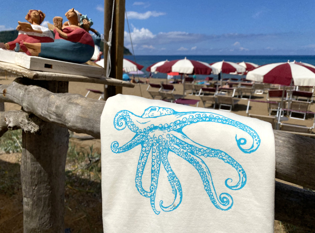 Weißes T-Shirt mit Siebdruckmotiv Oktopus hängt über Holzzaun