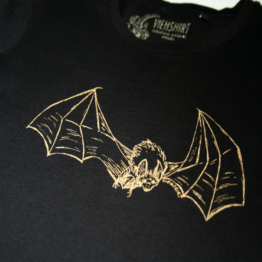 Detail eines Siebdruckmotivs Fledermaus, goldene Farbe auf schwarzem Stoff
