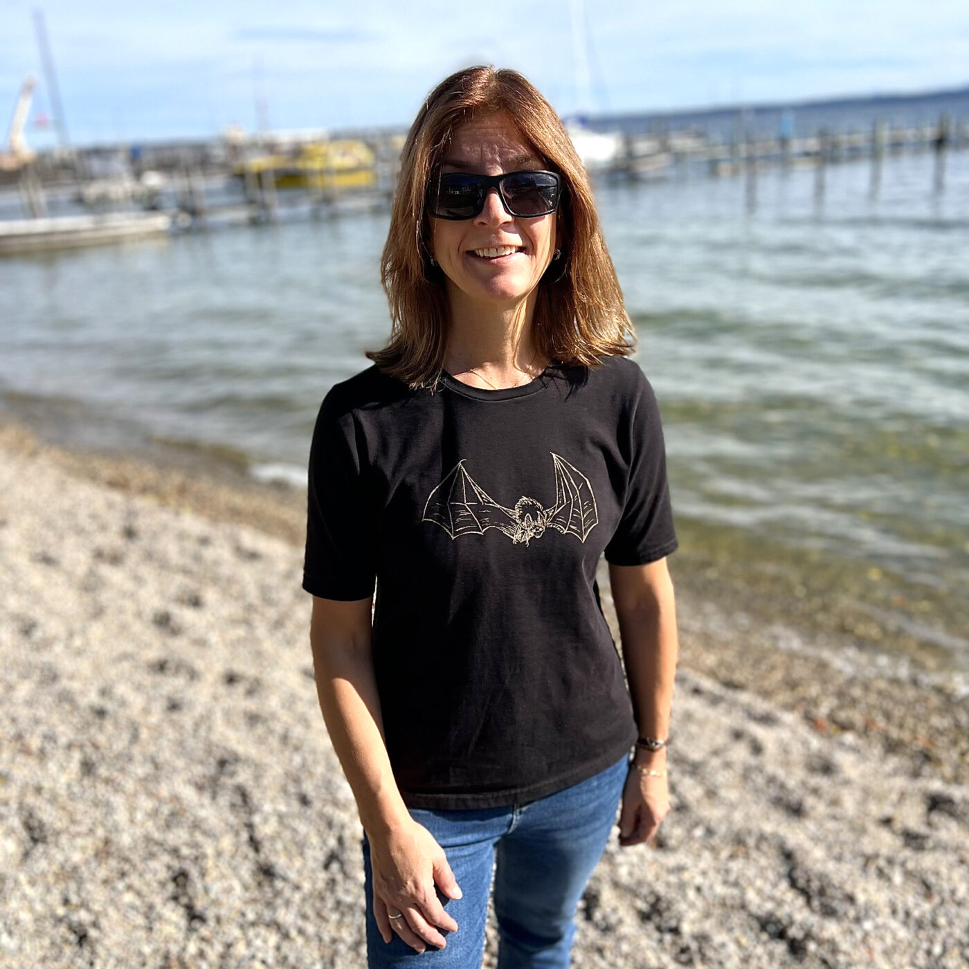 Frau am See trägt schwazes T-Shirt mit Siedruckmotiv Fledermaus