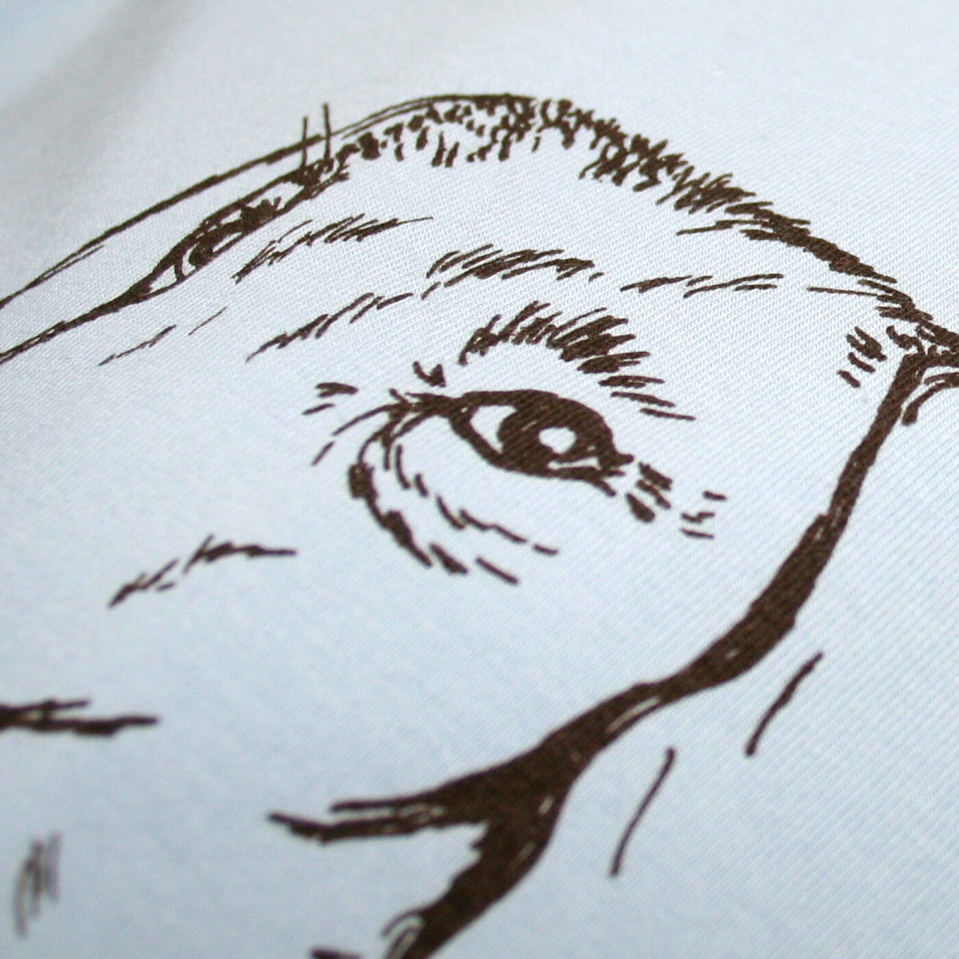 Detail eines hellblauen T-Shirts mit Siebdruckmotiv Dackelkopf