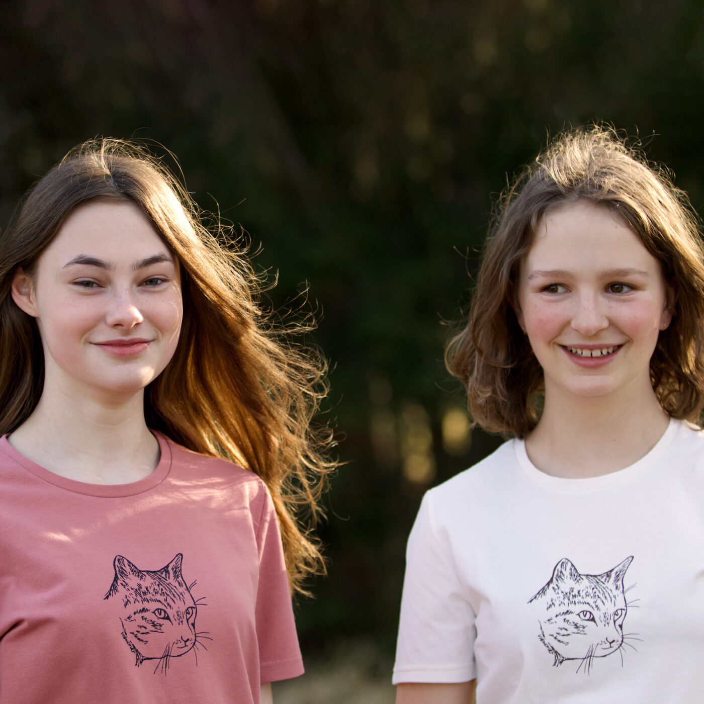 Zwei junge lächelnde Mädchen tragen T-Shirts mit Siebdruckmotiv Katzenkopf