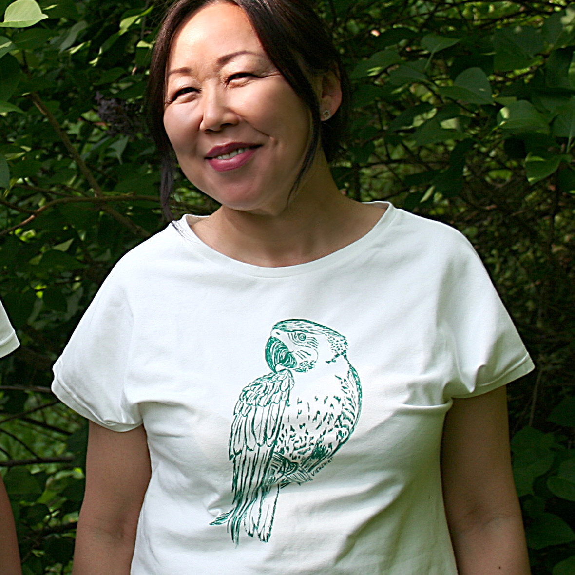 Frau trägt weißes Shirt mit grünem Papagei-Print