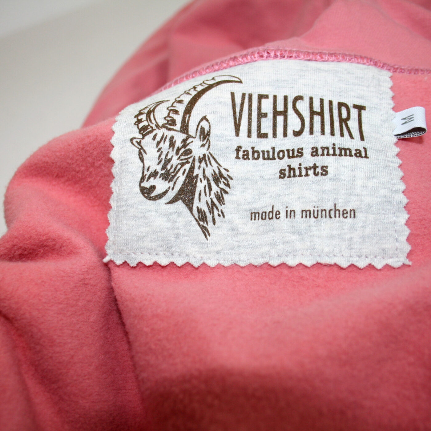 Detail des eingenähten Mode-Labels Viehshirt in einem flauschigen rosafarbenen Kleidungsstück